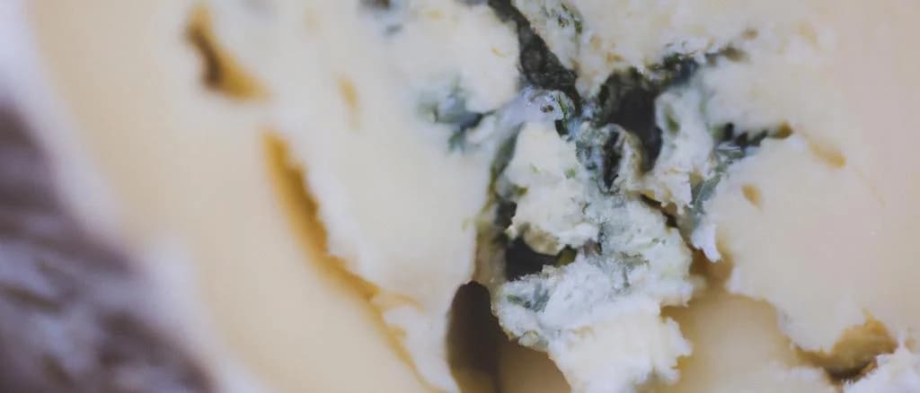 Assorted Stilton cheese varieties with traditional packaging on rustic wooden board