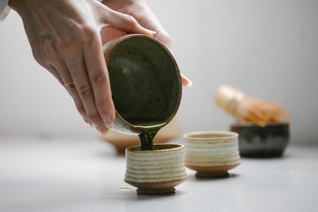Close-Up Photo of Person Pouring Freshly Made Matcha Drink