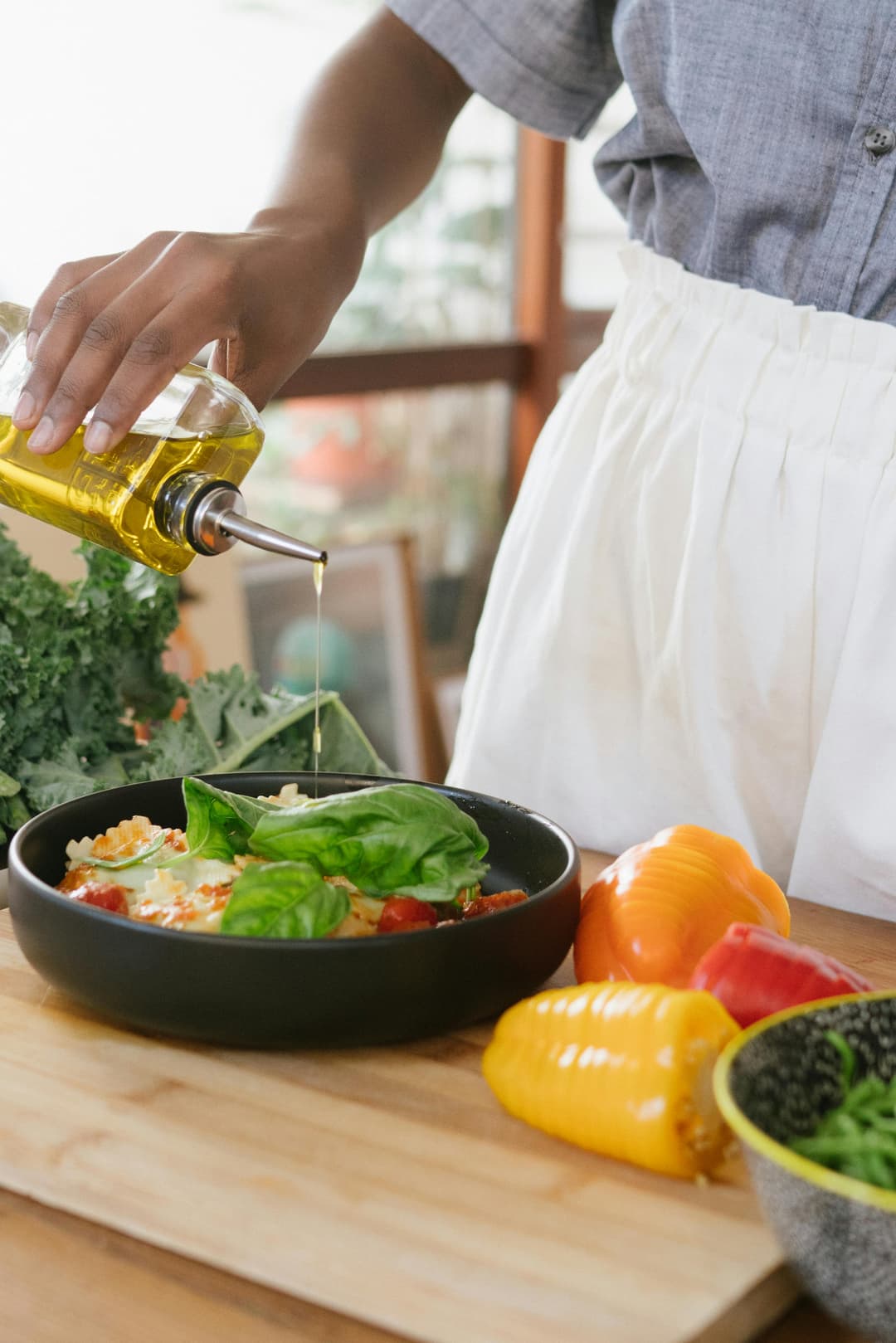 Lady pouring olive oil on salad